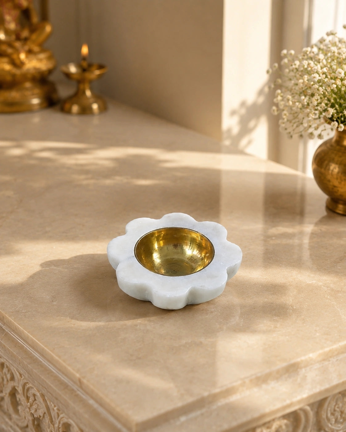 premium marble petal diya with lit wick flame surrounded by flowers and puja items