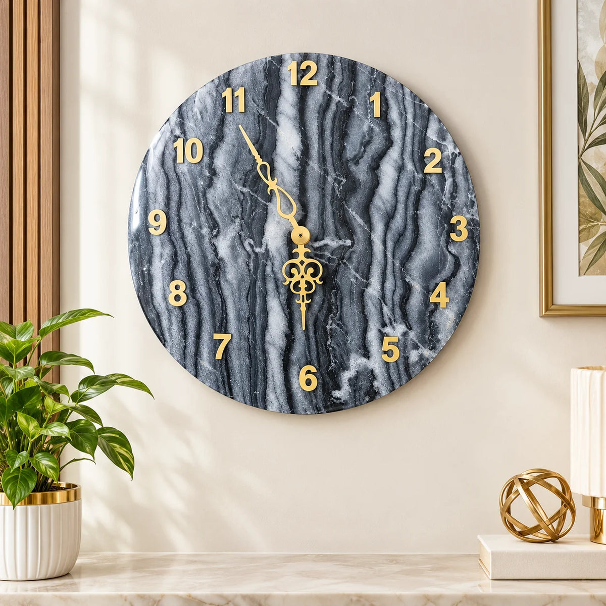 Close-up of a black and grey marble wall clock featuring distinctive natural stone veining, gold-tone raised numerals and intricate decorative golden clock hands.